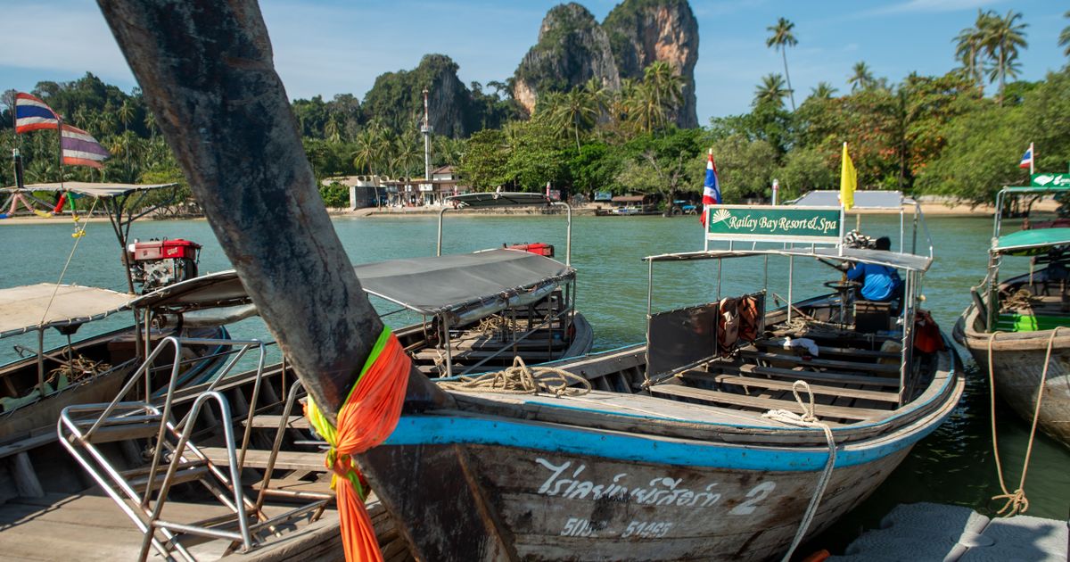 Traditional Thai longtail boats at Railay Beach with limestone cliffs, Krabi